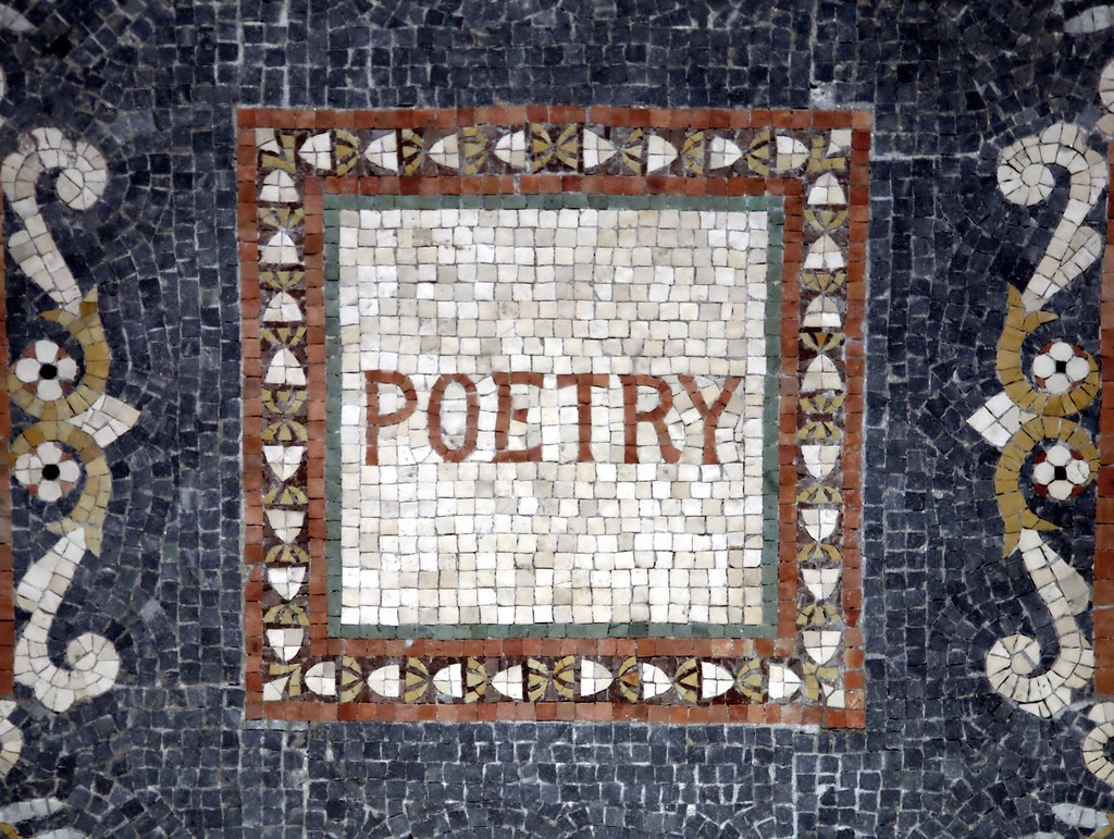 A stone mosaic panel spelling the word Poetry inside a decorative border